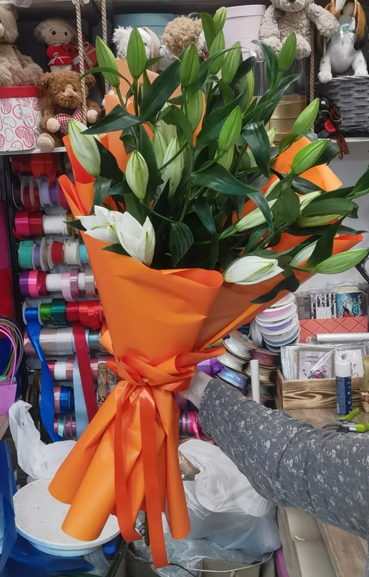 Букет № 32: 9 белых лилий высотой 100 см, оранжевая дизайнерская упаковка, атласные оранжевые ленты