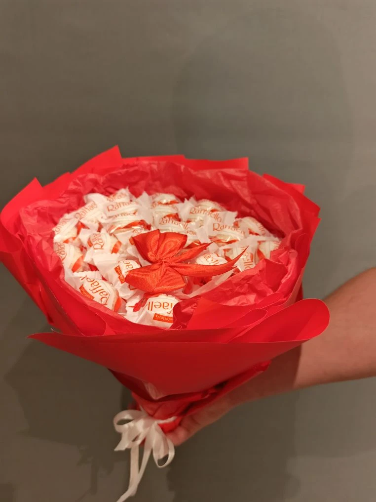 Сладкий букет № 7: 25 конфет Raffaello в ярко-красной композиции. Украшен красной бумагой тишью, белой атласной лентой и декоративным красным бантом.
                     Имеет ручку из бамбуковых шпажек. Эффектная цветочная композиция — сладкий подарок в Коломне