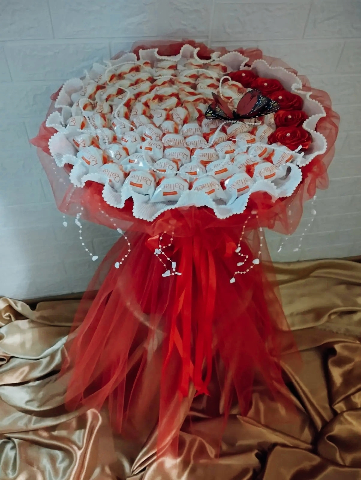 Сладкий букет № 14 из 75 конфет „Raffaello“ с декоративными элементами: бабочка, цветы, стразы.
                     Элегантная композиция с фатином и гофрированной бумагой. Цена: 5 500 ₽