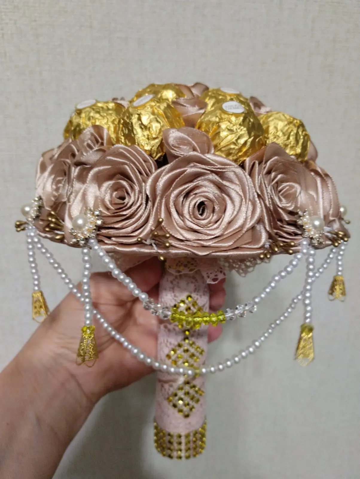 Сладкий букет № 4: 15 конфет Ferrero Rocher, украшенные атласной лентой, жемчужными бусинами, атласными розами бежево-розового оттенка и золотыми декоративными элементами. Ручка букета обёрнута тканью с
                     кружевным узором и декорирована золотыми стразами. Элегантный сладкий подарок в Коломне. Доставка в Коломне